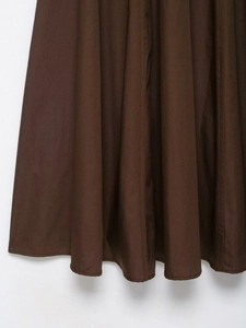 Detailed macro view of brown pleated midi dress fabric with natural texture and neat stitching