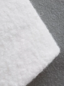 Close-up of soft white sherpa fleece fabric texture on a dark grey background