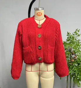 Detail of red chunky knit cardigan featuring gold embossed buttons and front patch pockets