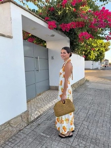 Detailed view of backless halter dress with orange print and tropical vacation vibes