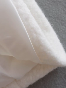 Detail of soft white faux sheepskin outer and smooth satin lining on a long warm coat