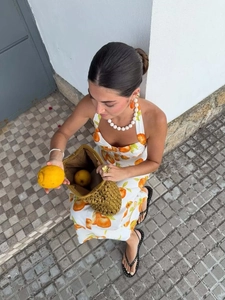 Detail of linen summer dress with orange citrus print and woven straw bucket bag