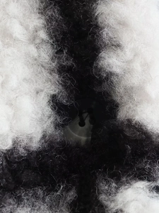 Close-up of black and white faux fur texture and a polished black button on the coat