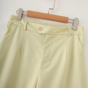 Detailed view of the waist, button, and pockets on these light green linen pants