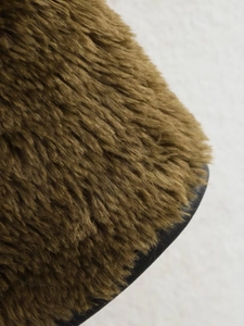 Detailed macro view of dense tan faux fur texture and smooth black lining on the jacket