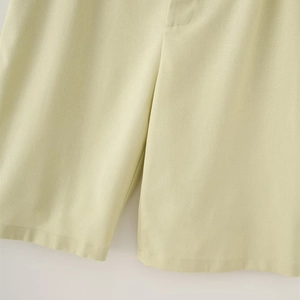 Detail view of lime green linen shorts showing fabric texture and neat stitching seams
