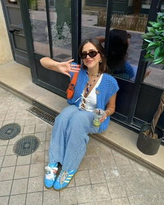 Detail of bright blue hand-crocheted vest paired with stylish blue striped wide-leg pants