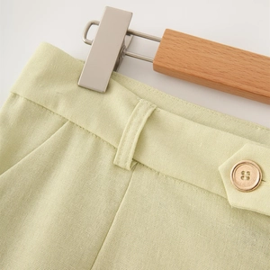 Detail view of light green linen shorts featuring amber button and neat stitching