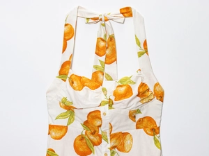 Detail of linen halter dress featuring vibrant orange citrus print and front buttons