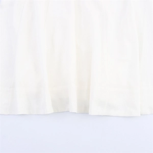 Détail de l'ourlet cousu d'une robe mi-longue blanche minimaliste en tissu impeccable