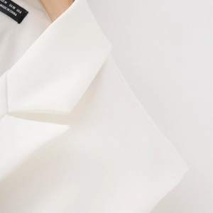 Dettaglio macro del colletto del blazer bianco e etichetta taglia EUR 38 e US 6