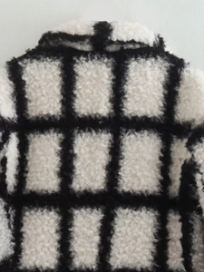 Close-up of black and white checkered plush fabric on a long wool blend winter coat