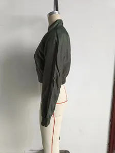 Detail of dark green bomber jacket with smooth satin finish and ribbed cuffs on a white mannequin