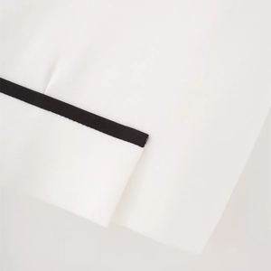 Dettaglio della trama in tessuto twill e bordino a contrasto nero sul gilet bianco fine