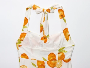 Detail of white halter neck dress with orange print and back bow tie decoration