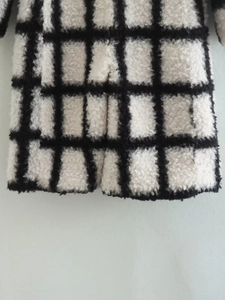 Detailed macro view of the thick black and white plaid plush faux fur coat texture