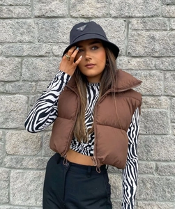 Detail of brown quilted puffer vest with stand collar and adjustable drawstring hem