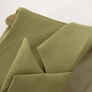 Gros plan du col en tweed vert avocat sur un gilet dos nu à coupe irrégulière chic