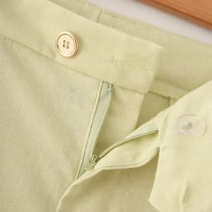 Detailed macro view of linen-blend shorts featuring zipper closure and metal button detail