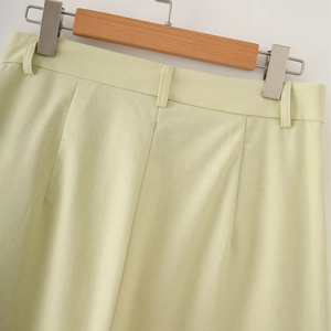 Detailed view of light green cotton linen shorts with belt loops and front pleat detail