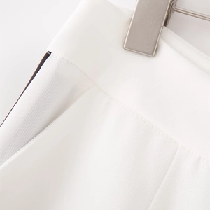 Dettaglio dei pantaloni bianchi con strisce laterali a contrasto e trama in twill