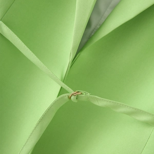 Detail of the light green blazer featuring a waist tie and elegant gold metal ring buckle