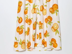 Detail of linen blend skirt with realistic orange print and single-breasted wooden buttons