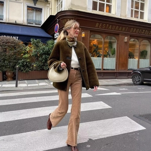 Chic women olive green faux fur jacket paired with khaki corduroy pants for autumn street style