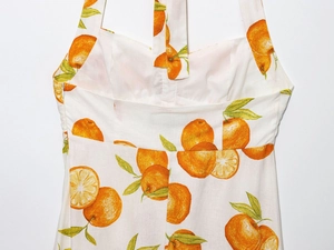 Detail view of linen blend summer dress featuring realistic orange and leaf print patterns
