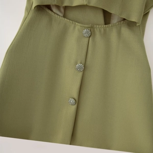 Détail du gilet vert olive avec boutons argentés tressés et découpes sur le devant