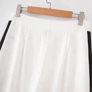 Dettaglio di pantaloni bianchi a vita alta con strisce nere laterali e pieghe