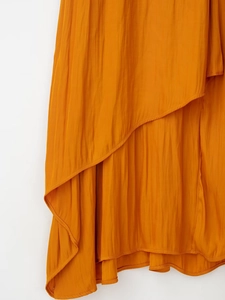 Détail de la robe midi en satin jaune gingembre avec texture plissée et ourlet asymétrique