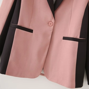 Detailed close-up of pink and black color-block blazer with sleek lapel and button detail