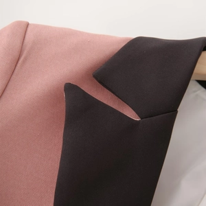 Detail view of pink and black contrast peak lapels on minimalist women suit blazer