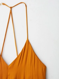 Gros plan des bretelles fines et du décolleté en V sur une robe midi satinée orange