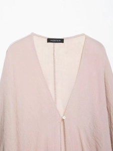 Détail d'un cardigan en ramie beige clair avec col en V profond et texture délicate