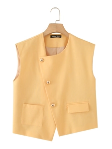 Detail of yellow cotton linen vest featuring gold metal buttons and asymmetric pockets