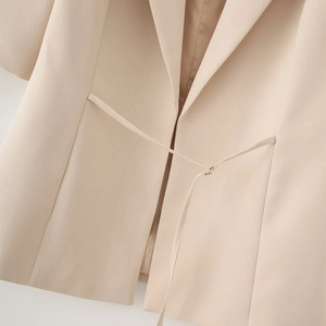 Close-up of beige blazer with notched lapel and elegant waist tie belt design