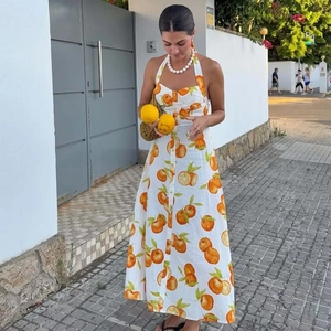 White linen halter dress with vibrant orange fruit print and summer vacation style