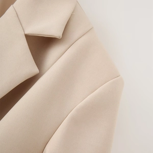 Macro shot of beige blazer shoulder showing twill fabric texture and notched lapel detail