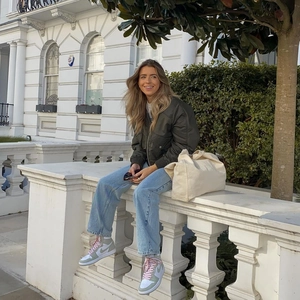 Army green bomber jacket paired with light blue straight jeans and sneakers