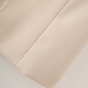 Detail view of beige blazer fabric showing fine texture and precise industrial stitching