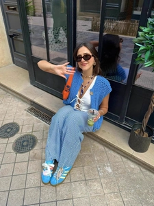 Women coarse knit blue vest paired with white tank top and striped straight trousers