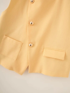 Detailed view of yellow linen vest with golden metal buttons and classic pocket tailoring