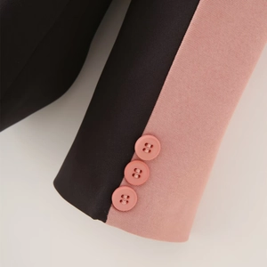 Detailed close-up of suit sleeve featuring pink contrast stitching and three round buttons