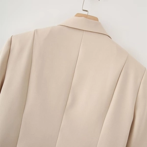 Detail view of the tailored back seams and collar structure on a beige blazer jacket
