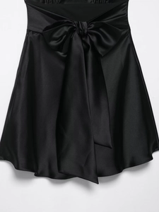 Detail of elegant black satin high waist skirt with a large decorative bow tie