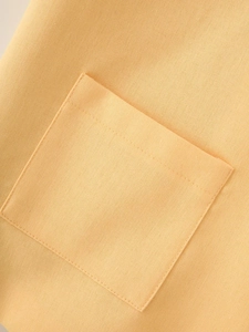 Detailed macro shot of a yellow cotton linen vest with a functional patch pocket