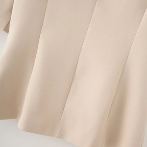 Macro shot of the pleated hem and fine twill texture on a beige tailored blazer