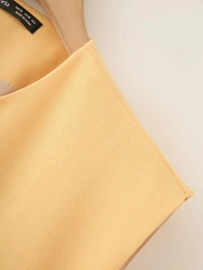Macro shot of cotton linen vest fabric texture and black size label on a wooden hanger